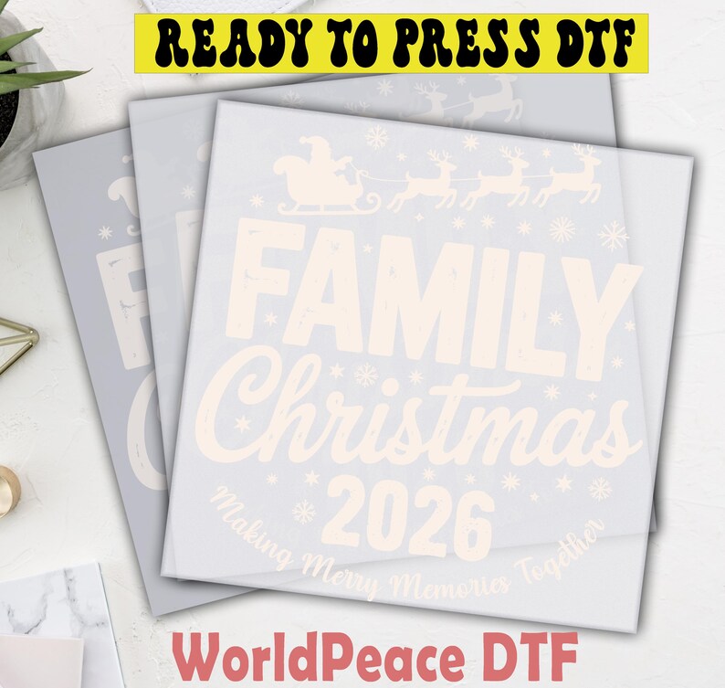 May include: A square DTF transfer sheet featuring a light-colored graphic with a Santa sleigh and reindeer silhouette, the text FAMILY Christmas 2026, and the phrase Making Merry Memories Together, accented by small snowflake icons throughout.