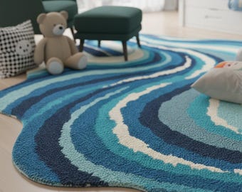 May include: A blue, wave-shaped rug with varying shades of blue and white. The rug has a textured surface and is placed on a light-colored wooden floor. A teddy bear and decorative pillows are nearby.