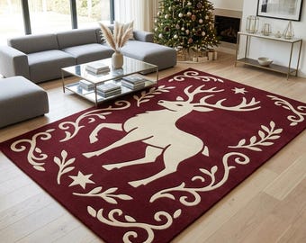 May include: A rectangular area rug featuring a deep red background with a large, cream-colored central graphic of a standing deer. The design is framed by cream-colored scrolling leaf patterns and small star shapes positioned at the corners.
