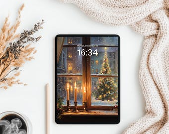 May include: A black tablet displays a winter scene with a Christmas tree and lit candles. The screen shows the time as 16:34 on Monday, December 18. A beige knitted blanket and dried plants are on a white surface.