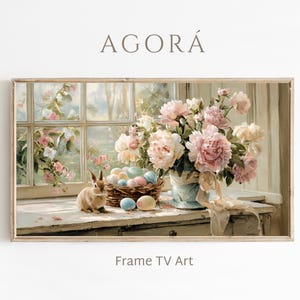 Puede incluir: Una impresión artística digital enmarcada que presenta una escena primaveral. Un conejito está sentado cerca de una cesta con huevos de Pascua en tonos pastel. Un jarrón con peonías rosas está junto a una ventana. El texto "AGORÁ" y "Frame TV Art" son visibles.