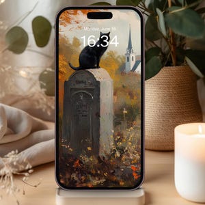 May include: A smartphone displaying a lock screen with a digital painting of a black cat sitting on a tombstone in an autumn landscape. The screen shows the time 16:34 and the date Monday, June 18. The phone is held upright on a light-colored stand.