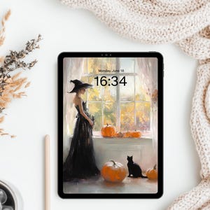 May include: A black tablet displaying a digital illustration of a person in a witch hat and black dress standing by a window with pumpkins and a black cat. The screen shows the text Monday, June 18 and the time 16:34 in a black sans-serif font.