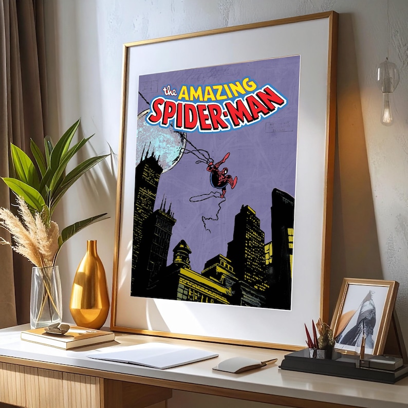 May include: Framed print of a vintage comic book cover featuring Spider-Man. The title "The Amazing Spider-Man" is displayed in red and white. Spider-Man is depicted swinging over a cityscape with a purple sky and a full moon.