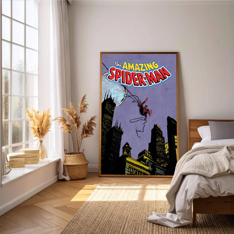 May include: A framed poster featuring the comic book cover of "The Amazing Spider-Man." The artwork depicts Spider-Man swinging above a cityscape with a purple background. The poster is displayed in a well-lit room with a window and bed.