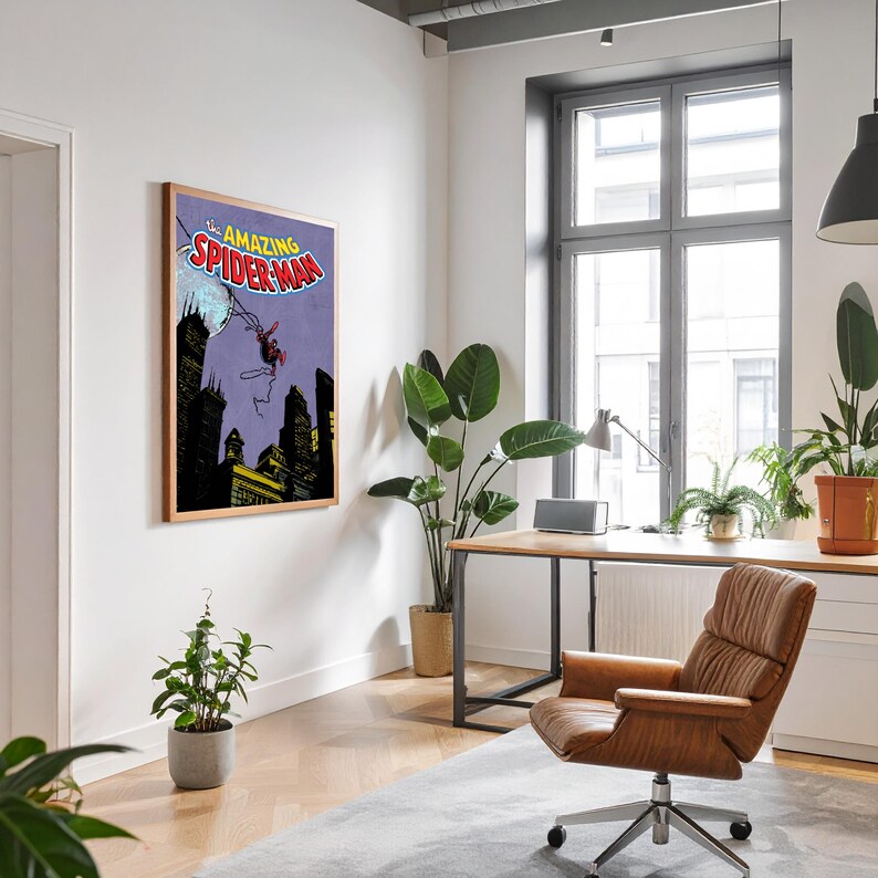 May include: A framed comic book art print of The Amazing Spider-Man. The artwork features Spider-Man swinging over a city skyline with a purple background. The frame is a light brown color and is hanging on a white wall.