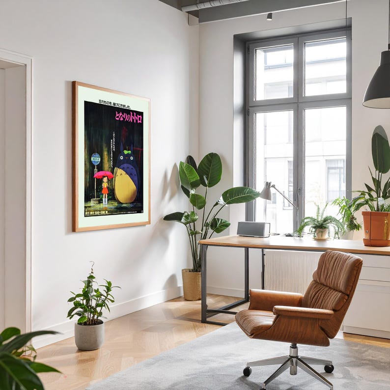 May include: A framed poster featuring a scene from the animated film "My Neighbor Totoro." The artwork depicts a girl with an umbrella, a large Totoro character, and Japanese text. The poster is displayed in a well-lit office setting.