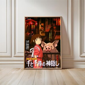 May include: Framed poster featuring a scene from the animated film "Spirited Away." The artwork depicts a young girl in a red outfit, standing near a pig. The background shows a nighttime cityscape with Japanese text. The poster is in a wooden frame.