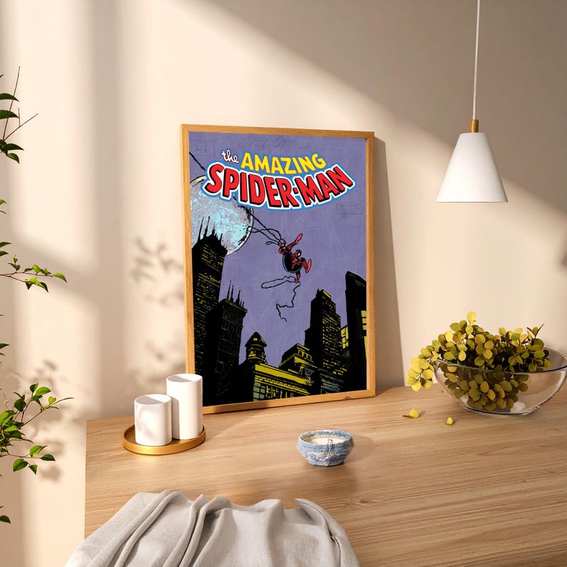 May include: A framed print of The Amazing Spider-Man comic book cover. The artwork features Spider-Man swinging through a city skyline with a purple background. The title is in red and blue.