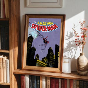 May include: Framed print of a vintage comic book cover featuring Spider-Man swinging through a city at night. The title "The Amazing Spider-Man" is displayed in red and blue. The artwork is set against a purple sky.