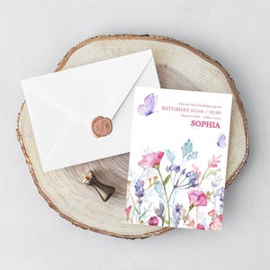 May include: A white invitation card with floral watercolor design, a matching envelope with a wax seal, and a small gold-colored stamp. The invitation text reads "Join me for a birthday picnic" and the name "Sophia".