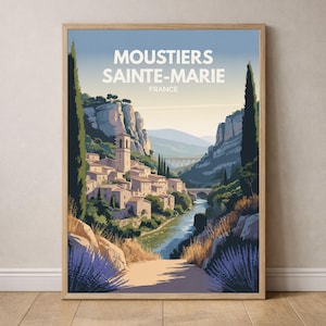 Peut inclure: Une affiche encadrée représentant Moustiers Sainte-Marie, France, dans un style vintage. L'image montre un village avec une rivière, un pont et des falaises. L'affiche est dans un cadre en bois clair, évoquant le voyage et la nostalgie.
