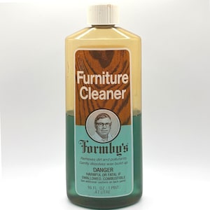 May include: A vintage bottle of Formby's Furniture Cleaner. The label features the text "Furniture Cleaner" in white, a portrait of a man, and the brand name. The bottle contains a green liquid and is 16 fl oz (1 pint).