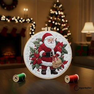Puede incluir: Una decoración navideña bordada, de forma redonda, que representa a Papá Noel con un traje rojo, sosteniendo un saco. El diseño incluye flores de pascua y acebo. Dos carretes de hilo, uno verde y otro rojo, están sobre la mesa. Un árbol de Navidad y una chimenea están en el fondo.