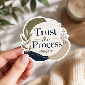 Może przedstawiać: Wykrawana naklejka z napisem "Trust the Process" ciemnoniebieską czcionką. Projekt zawiera abstrakcyjne kształty w kolorze oliwkowej zieleni, granatu i beżu, podkreślone delikatnymi botanicznymi ilustracjami liści oraz cienkich łodyg.