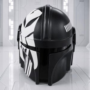 May include: A black helmet with white graphic designs. The helmet has a rounded top and a visor. White vertical lines are on the upper right side. The helmet is likely for cosplay or costume use.