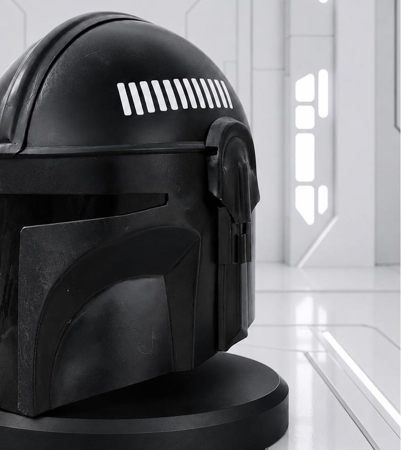 May include: A black helmet with a matte finish, featuring a series of white vertical lines on the upper right side. The helmet has a detailed design with a visor and a rounded shape, set against a bright, white background. The helmet is likely a collectible or cosplay item.