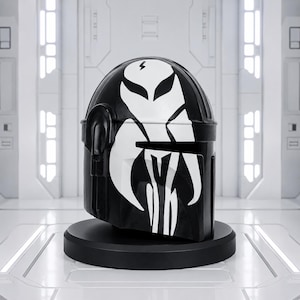 May include: A black helmet with a white graphic design, including a lightning bolt and stylized avian features. The helmet is displayed on a black circular stand, set against a futuristic white backdrop.