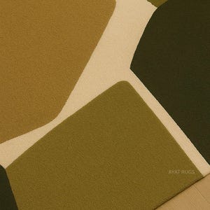 May include: A close-up of a modern area rug with an abstract design. The rug features geometric shapes in shades of olive green, brown, and cream. The rug is made of a soft, textured material and is suitable for living rooms and bedrooms.