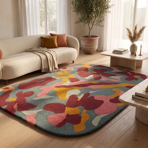 May include: A large, rectangular area rug with rounded corners featuring an abstract, organic pattern in shades of muted blue, deep red, bright yellow, and soft pink. The rug has a dense, textured pile surface with a multi-colored floral-inspired design.