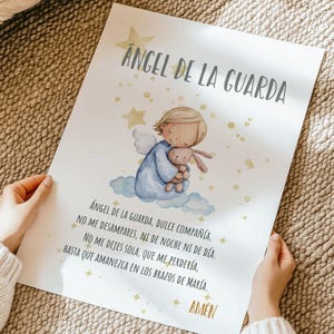 May include: A print featuring a watercolor illustration of an angel in a blue robe holding a stuffed bunny. The text "Angel de la Guarda" is at the top, with a prayer below. Gold stars and accents decorate the print.