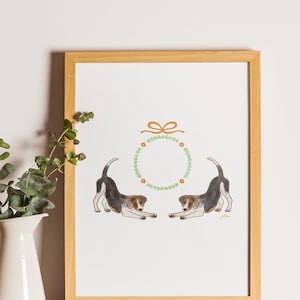 May include: A framed art print featuring two watercolor beagle dogs in playful poses. A green wreath with orange flowers and a gold bow are above the dogs. The frame is made of light-colored wood.