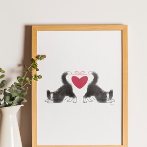 May include: A framed print featuring two black and white cats with their tails forming a heart shape. A red heart with a pink bow is centered between the cats. The artwork is in a wooden frame.