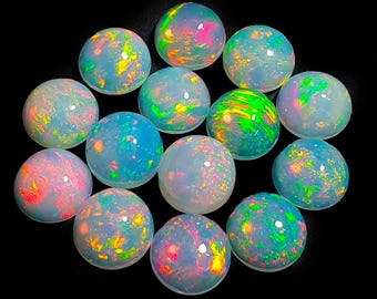 May include: A collection of fourteen round opals, each displaying a unique play of color. The opals range in color from white to blue, with flashes of pink, green, and yellow. The gemstones are set against a black background.