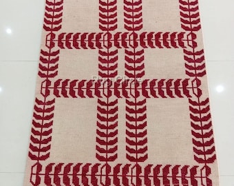 May include: A rectangular rug with a cream-colored background and a repeating pattern of red leaf-like shapes. The design creates a grid-like structure. The rug has a fringed edge and the text "RUG CIRCLE" in a circular logo.