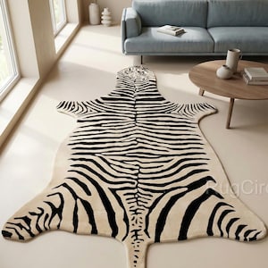 Puede incluir: Una alfombra con estampado de cebra en una habitación con un sofá azul claro y una mesa de centro de madera. La alfombra tiene forma de piel de cebra, con rayas negras sobre un fondo crema. La habitación tiene grandes ventanas y paredes de color neutro.
