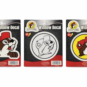 May include: Three window decals featuring the Buc-ee's beaver mascot. The decals are on black backing cards with red accents. Each decal has the words "Window Decal" printed on it.