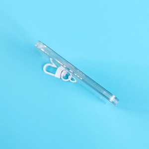 May include: A clear, rectangular phone case with a white clip is angled across a light blue background. The case appears to be made of transparent plastic, offering a view of the phone's back.