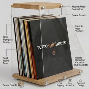 Può includere: Un espositore per dischi in acrilico trasparente con base e piano in legno massello. La custodia contiene dischi in vinile e presenta il testo "retrospinhouse" sul davanti. Il design include connettori metallici moderni e protezioni per viti.