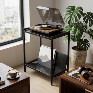 May include: A black marble-topped side table with a metal frame and a lower shelf holding vinyl records. A wooden turntable with a clear dust cover sits on the top surface. The table features a sleek design with a dedicated slot for storage.