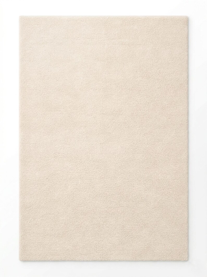 A studio product shot of a rectangular, cream-colored hand-tufted rug with a soft, plush texture and uniform pile, isolated against a clean white background.