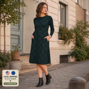 May include: A long-sleeved, knee-length dress in a dark green and black tartan pattern. The dress features a round neckline, a fitted bodice, a flared skirt, and two side pockets. It is paired with black leather ankle boots.