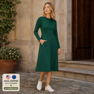 Può includere: Un abito midi verde scuro a tinta unita con maniche lunghe, scollo rotondo, corpetto aderente e gonna svasata. L'abito presenta tasche laterali funzionali ed è abbinato a semplici scarpe da ginnastica bianche per un look completo.