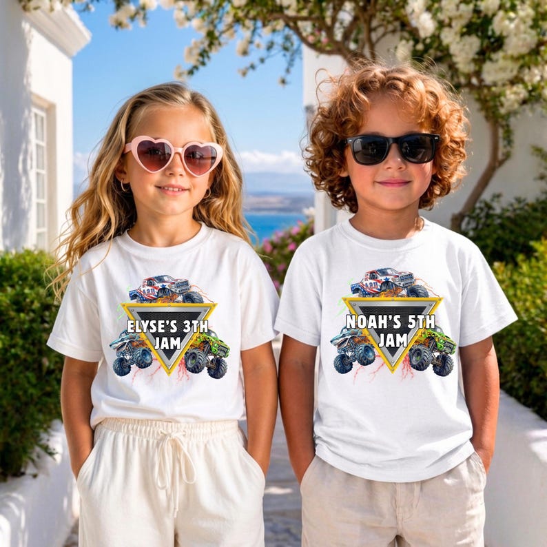May include: Two children wearing white t-shirts with a monster truck graphic. The shirts have a yellow triangle with the text "ELYSE'S 3TH JAM" and "NOAH'S 5TH JAM". The shirts feature a red, white, and blue monster truck design.