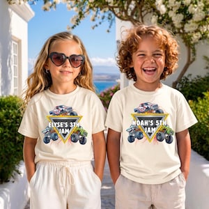 May include: Two children wearing cream t-shirts with a monster truck graphic. The graphic includes a monster truck, a yellow triangle, and the text "ELYSE'S 3TH JAM" and "NOAH'S 5TH JAM". The girl is wearing heart-shaped sunglasses.