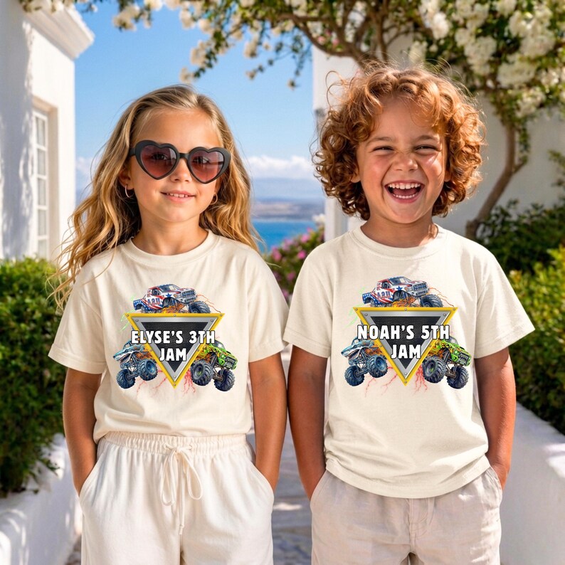 May include: Two children wearing cream t-shirts with a monster truck graphic. The graphic includes a monster truck, a yellow triangle, and the text "ELYSE'S 3TH JAM" and "NOAH'S 5TH JAM". The girl is wearing heart-shaped sunglasses.