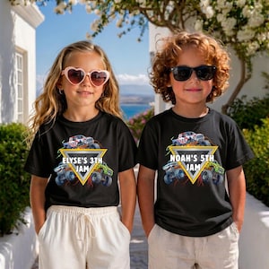 May include: Two children wearing black t-shirts featuring a monster truck design. The shirts display the text "ELYSE'S 3TH JAM" and "NOAH'S 5TH JAM" within a yellow triangle. The background shows a blue sea and white buildings.