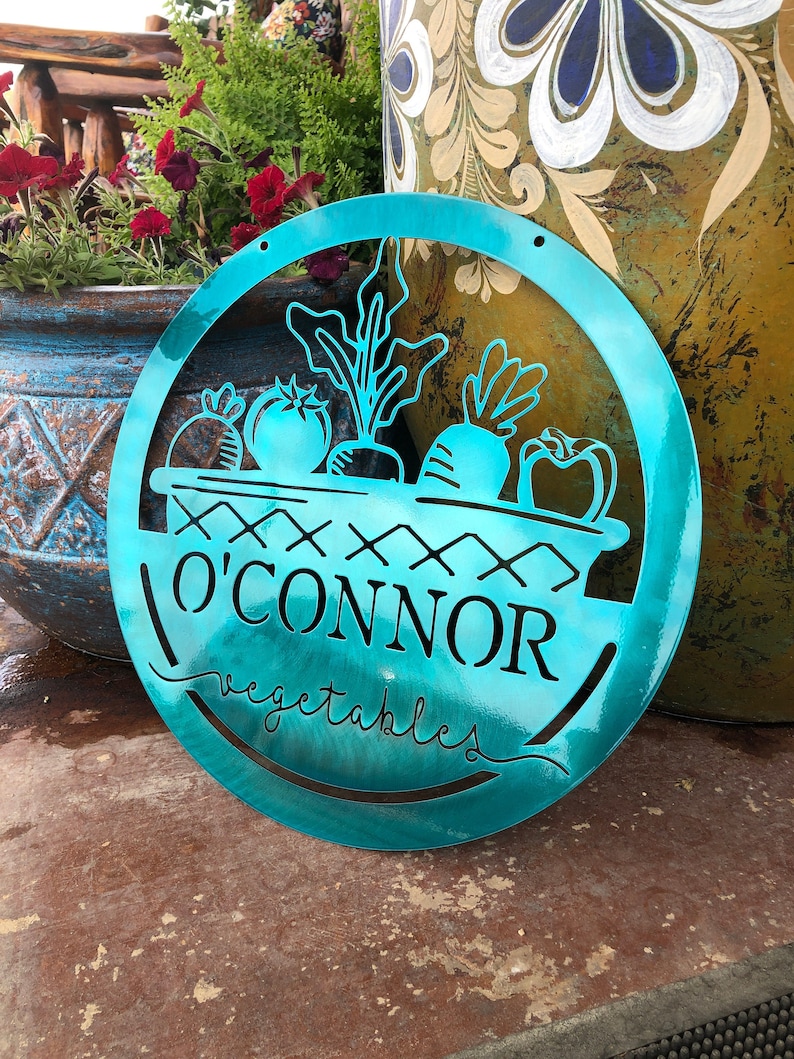 May include: A turquoise blue metal sign with a basket of vegetables and the text "O'Connor Vegetables".