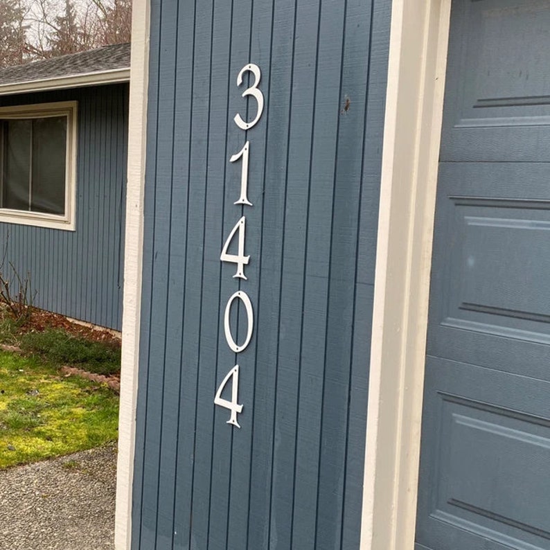 Pu&ograve; includere: Primo piano di un cartello con il numero civico 31404, visualizzato in bianco su una superficie di legno blu.