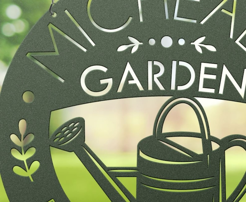 May include: Dark green metal garden sign with the word "GARDEN" in large, cut-out letters. The sign features a watering can and decorative leaf accents. The name "MICHEA" is above the word "GARDEN".