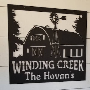May include: Black metal sign with a white silhouette of a barn, windmill, and trees. The sign reads "Winding Creek The Hovan's".