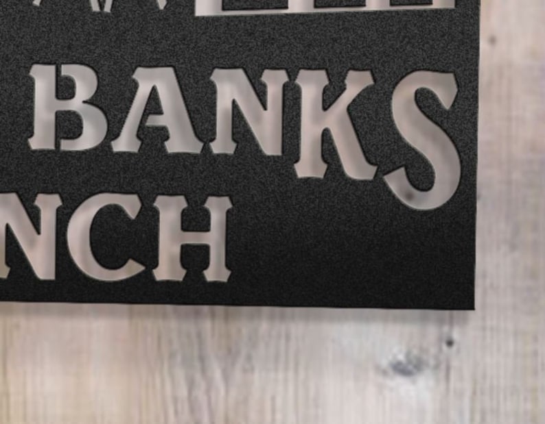 May include: A black metal sign with white lettering that reads "The Banks Ranch".
