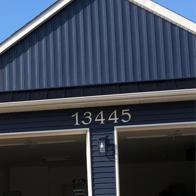 Pu&ograve; includere: Una casa blu con finiture bianche e un portone del garage. Il numero civico 13445 &egrave; visualizzato sulla facciata della casa.