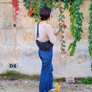 Festival-ready crochet sling bag worn crossbody – eco-friendly paper yarn bag with zipper closure and soft fabric lining.