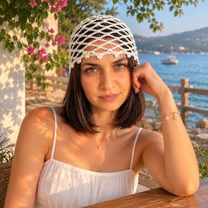 May include: A white crochet skull cap featuring an open diamond-shaped mesh pattern with a scalloped edge. The headwear is constructed from thin yarn and sits snugly on the head, providing a textured, lightweight appearance for the wearer.