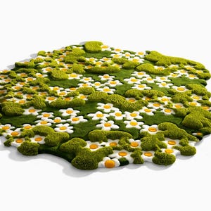 May include: A whimsical, green rug shaped like a field of flowers. The rug features white daisies with yellow centers and patches of textured green, resembling moss. The rug is on a white background.